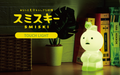 A promotional image featuring a 'Smiski Touch Light' with a depiction of a SMISKI glowing in a dimly lit room. The character is illuminated in a soft, green hue, and the text 'TOUCH LIGHT' is visible.